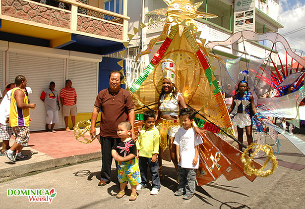 Карибская девушка в ярком карнавальном костюме фотографируется с детьми и туристами. Фото Карибского Карнавала в 2009 на Карибском острове Доминика